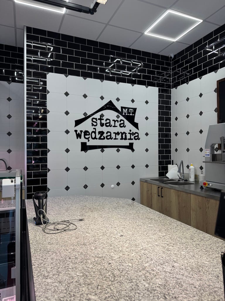 Wnętrze sklepu Starej Wędzarni — logo na ścianie i stanowisko krojenia